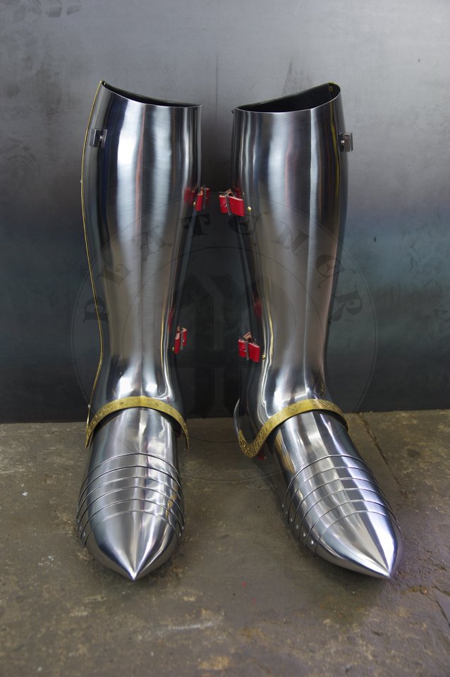 English style leg harness with fully closed cuisses, full greaves with characteristic line around outside ankles. Demi-greaves connected with greaves on rotary pin. Made of medium carbon steel of various thickness from 1 mm up to 1,5 mm. Heat hardened and tempered up to 42 HRC. Brass bands decoration motive based on example visible on Henry V tournament helm. Hand made steel buckles in set./Osony ng w stylu angielskim z w peni zamknitymi nabiodrkami, nagolennicami z charakterystyczn lini wok zewntrznej kostki. Demi-greave poczony z nagolennicami poprzez obrotowy pin. Wykonane ze stali redniowglowej rnej gruboci od 1 mm do 1,5 mm. Hartowane i odpuszczane do 42 HRC. Mosine listwy dekoracyjne z motywem wzorowanym na hemie turniejowym Henryka V. W zestawie rcznie robione sprzczki stalowe.